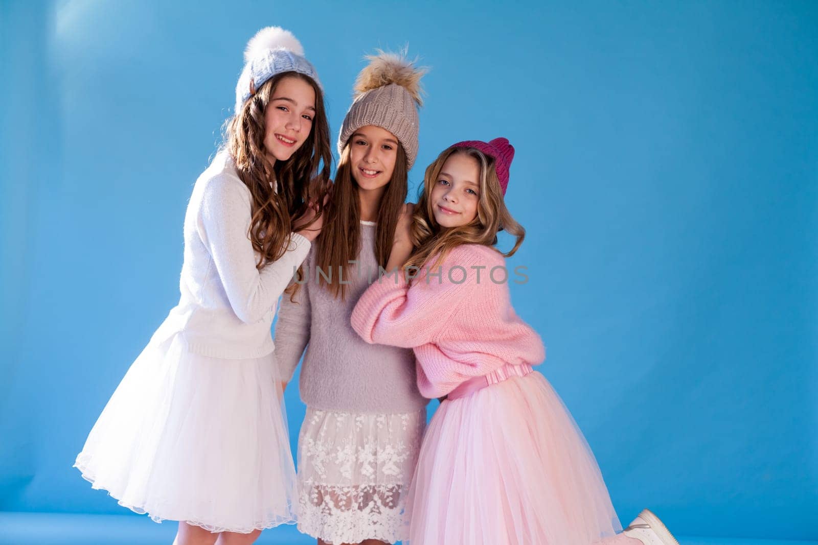 Three beautiful fashionable girl girlfriends in a winter snow cap by Simakov