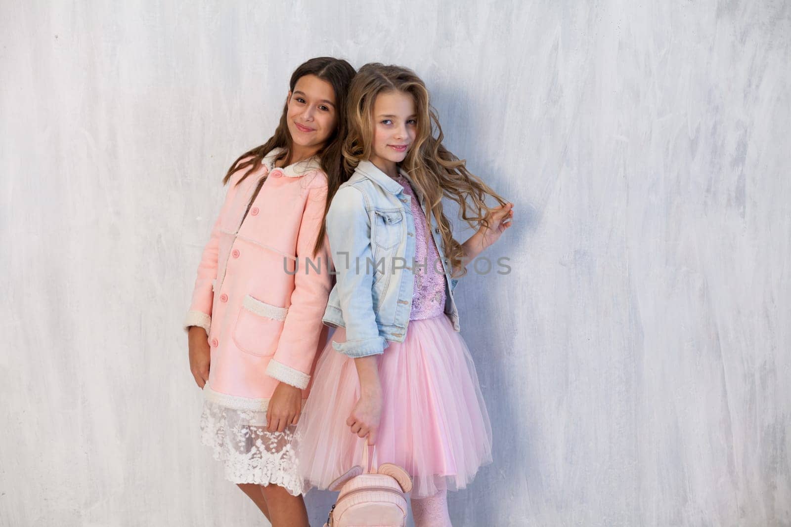 Portrait of two beautiful girl girlfriends in white pink clothes