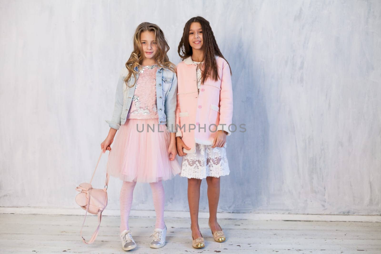 Portrait of two beautiful girl girlfriends in white pink clothes