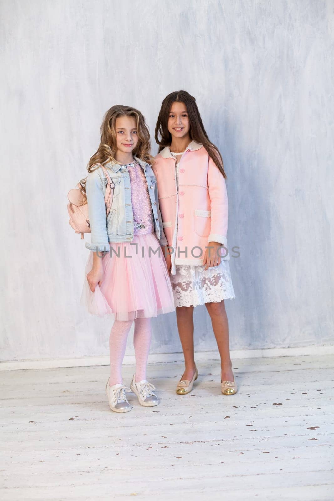 Portrait of two beautiful girl girlfriends in white pink clothes