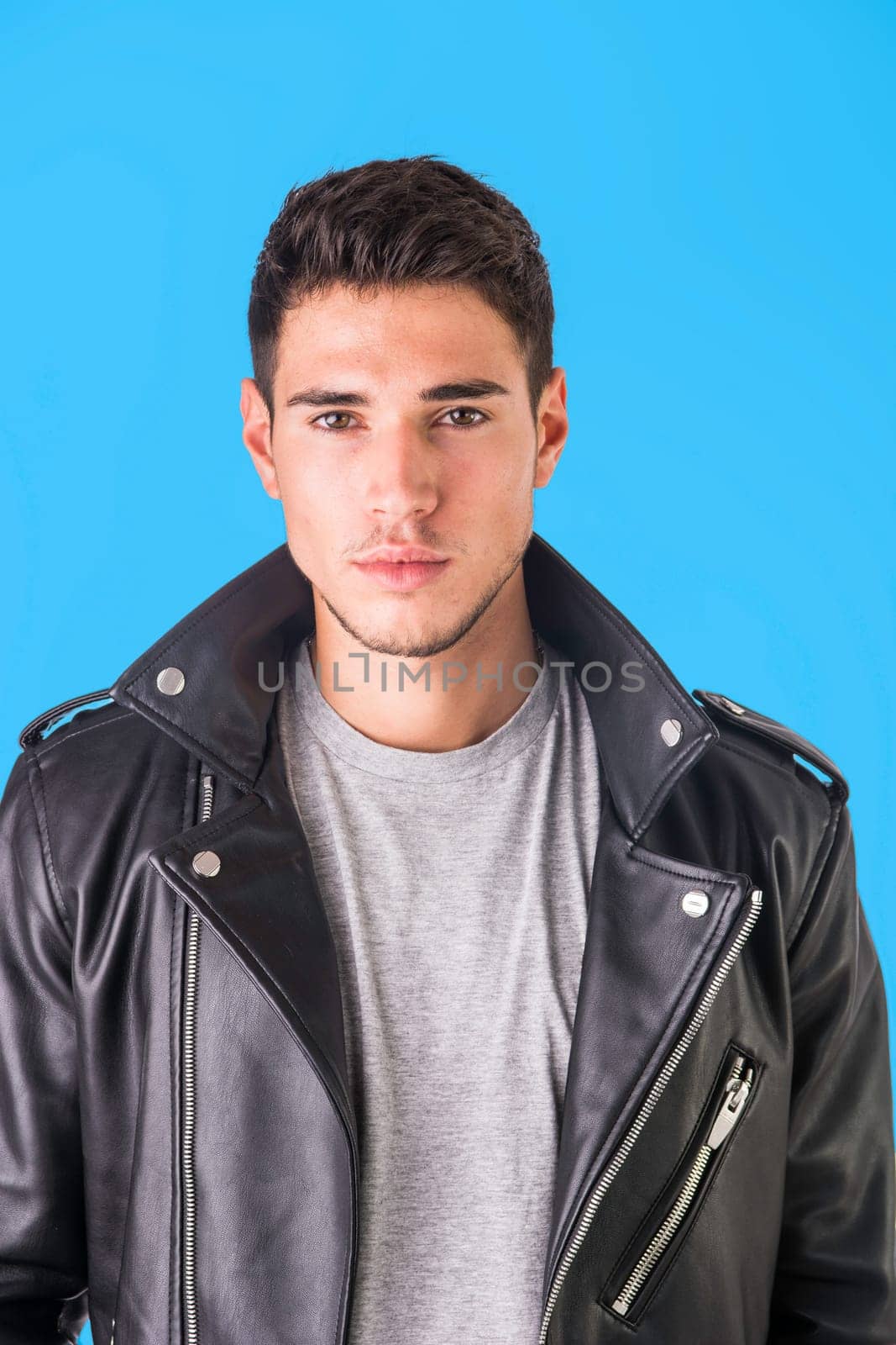 Young handsome man standing in studio shot, wearing black leather jacket and jeans