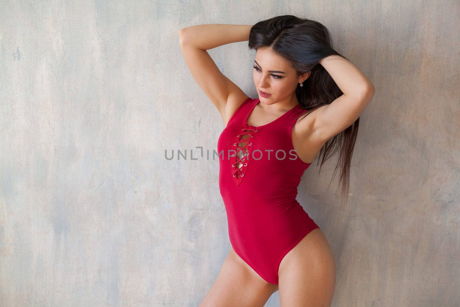 fashionable girl in red body posing on grey background by Simakov