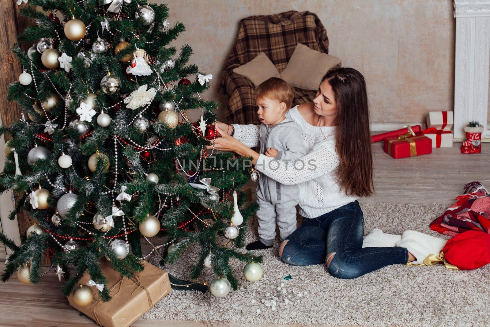 mother and little boy at Christmas tree with gifts 1 by Simakov
