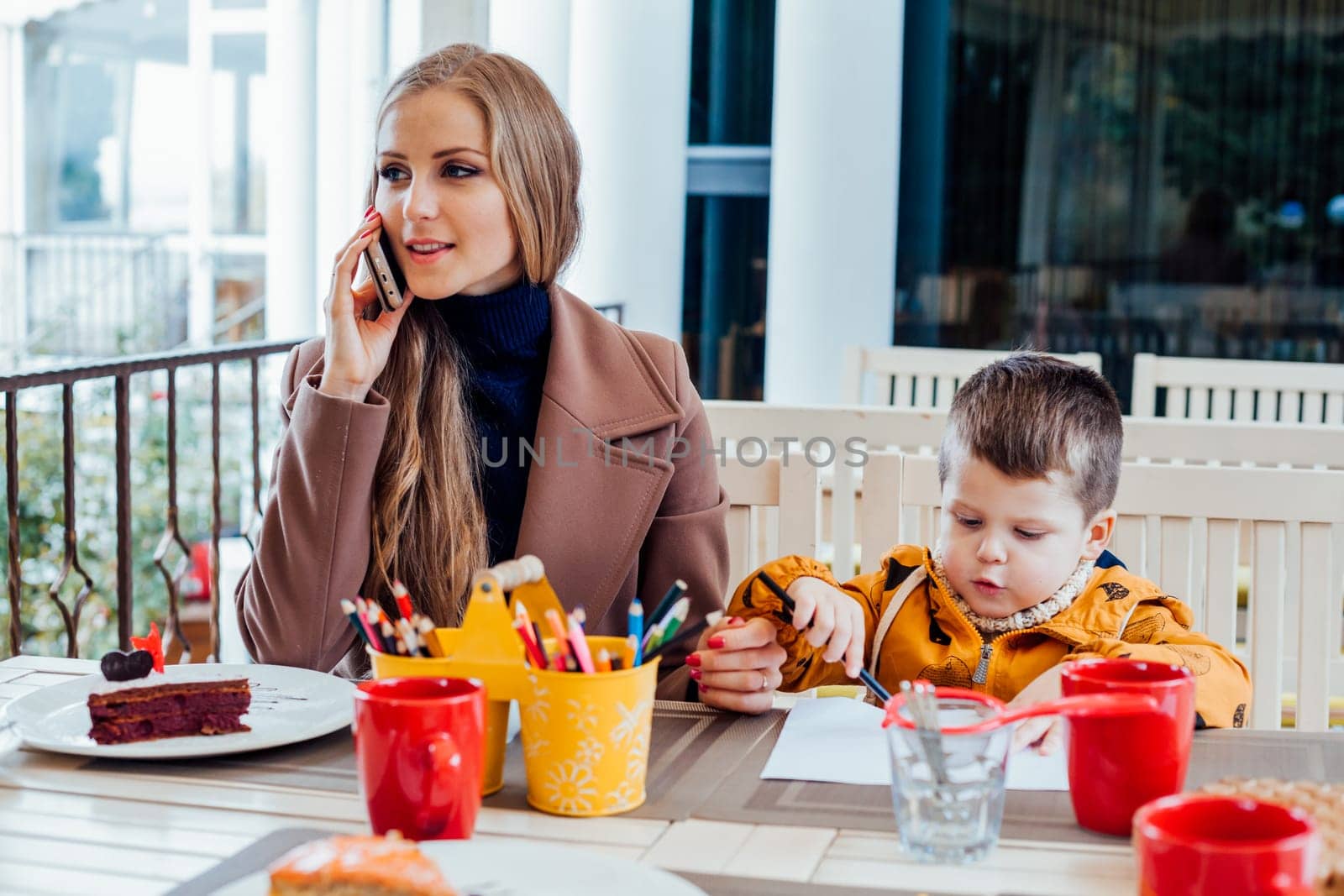 Restaurant mom with son talking on the phone by Simakov