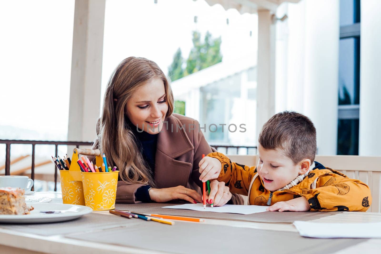 woman teaches the boy to draw with colored pencils by Simakov