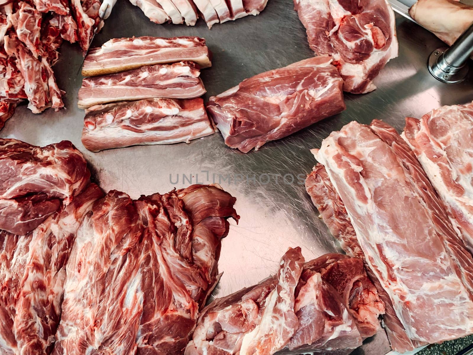 lots of fresh pork meat for eating on a metal table as a background by Simakov