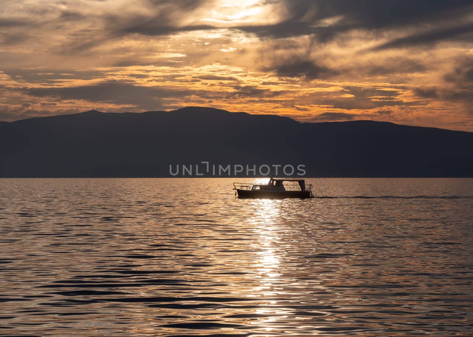 small tourist boat sails on a lake at sunset