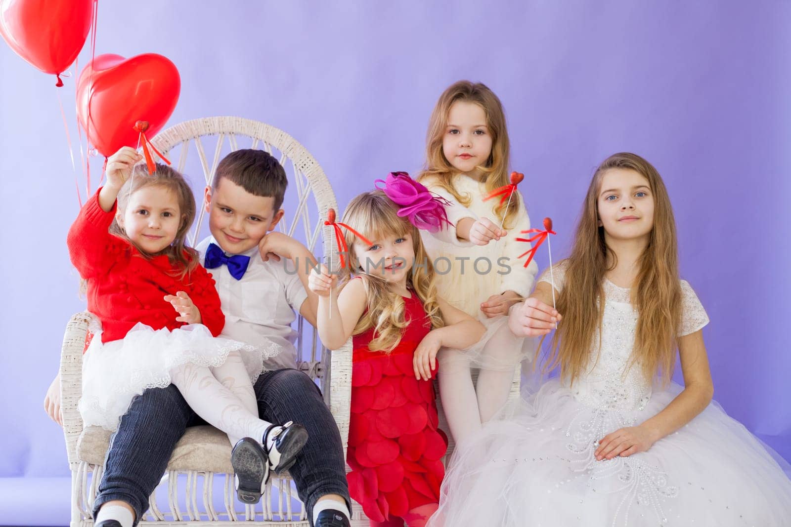 Boy and girls with red heart-shaped balloons on holiday by Simakov