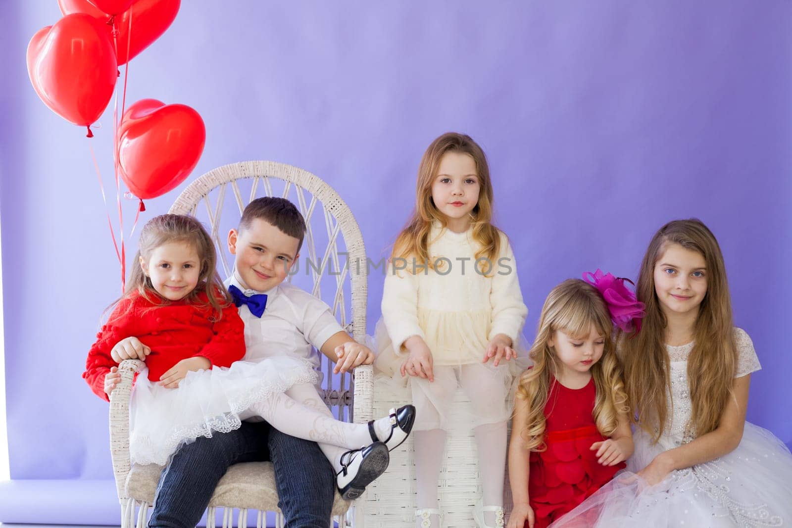 Boy and girls with red heart-shaped balloons on holiday by Simakov