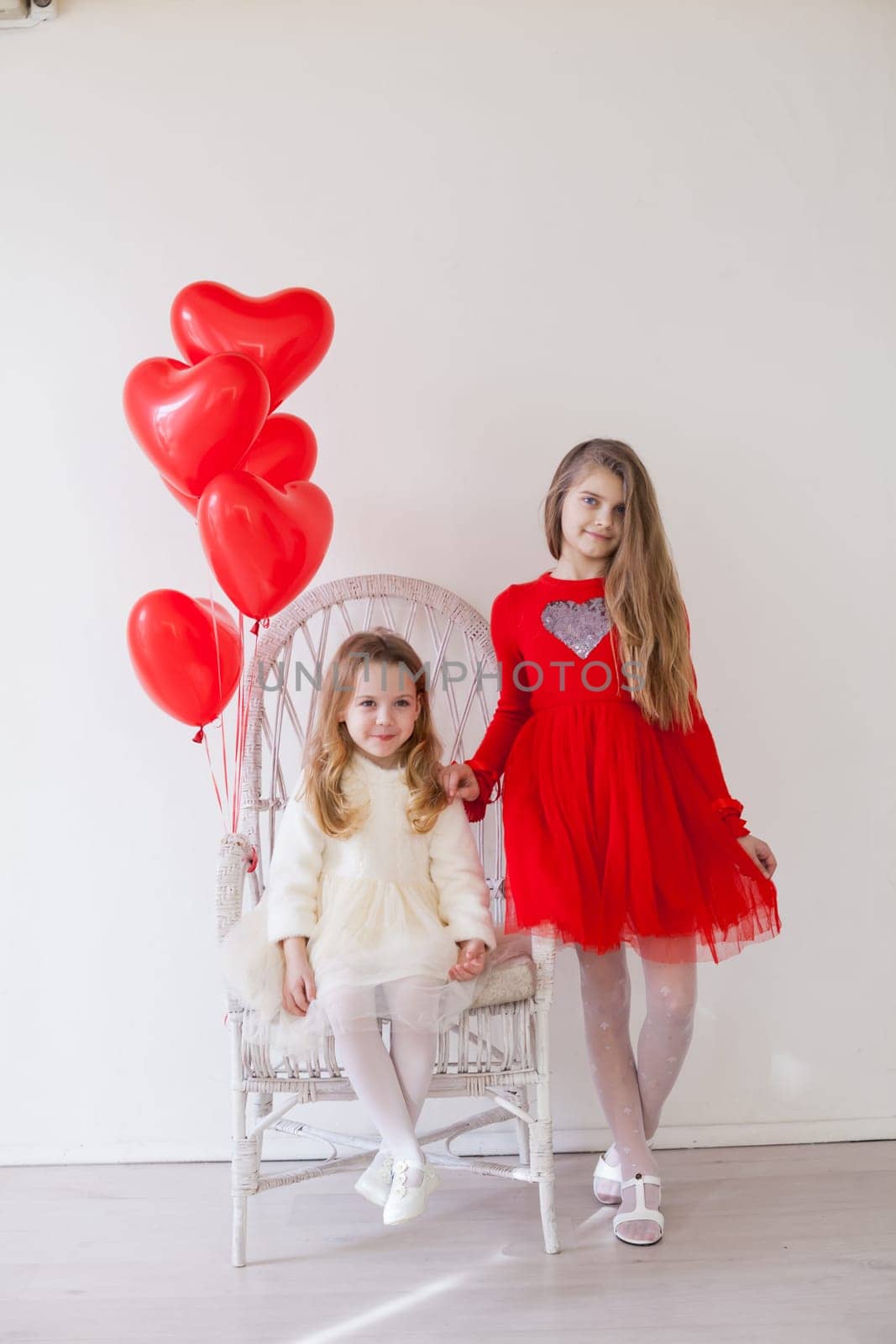Two girls with red heart-shaped balloons on Valentine's Day celebrations by Simakov