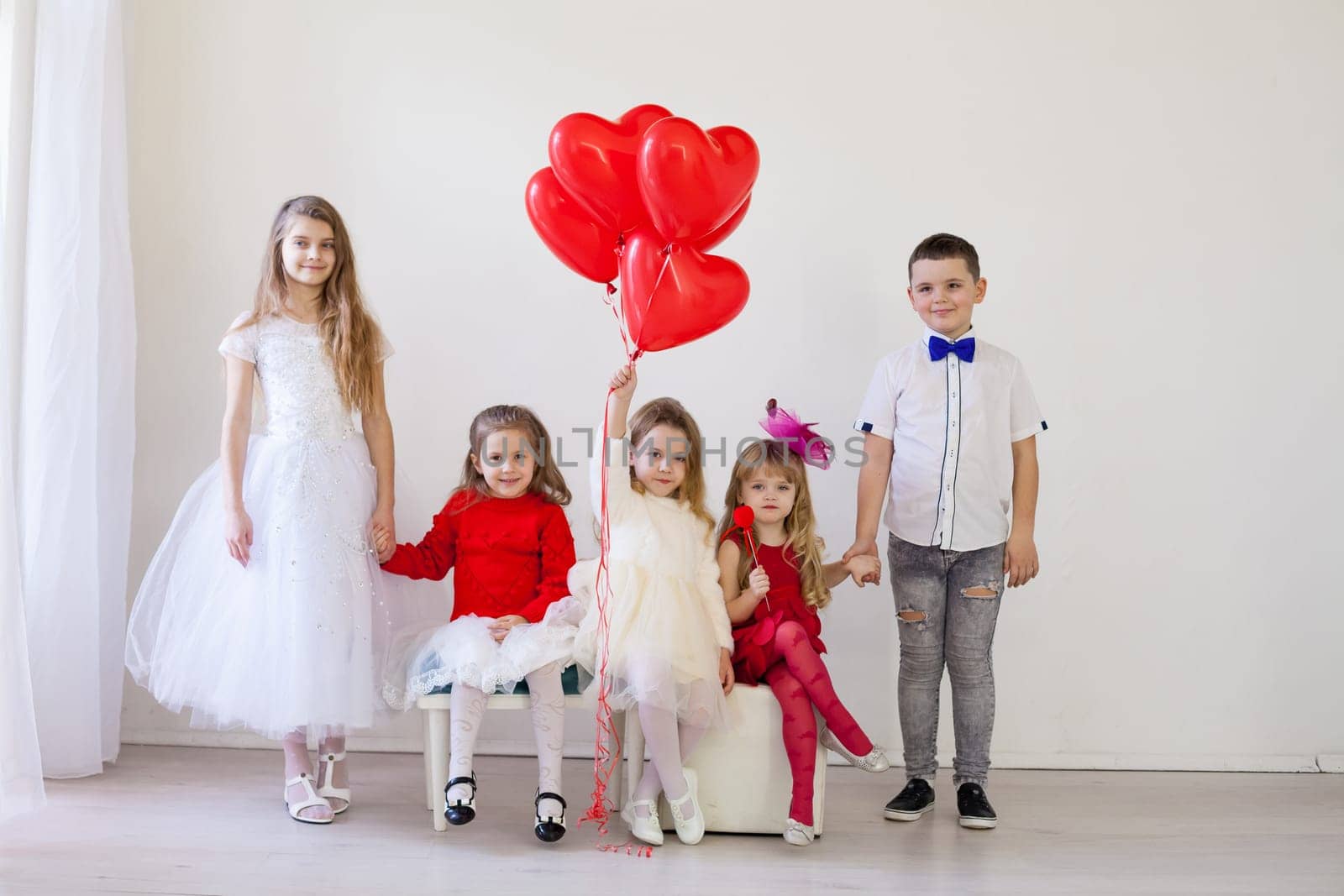 Boy and girls friends on red white birthday party by Simakov