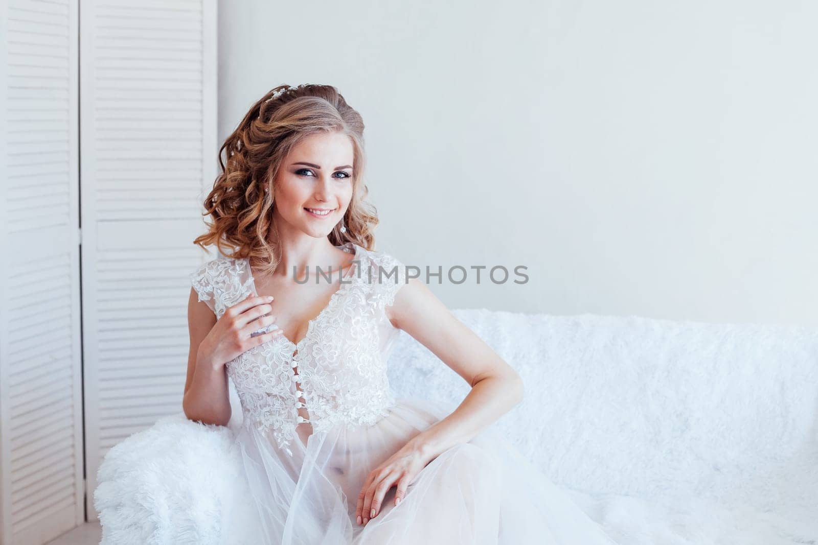 beautiful bride sitting on a white couch in lingerie wedding