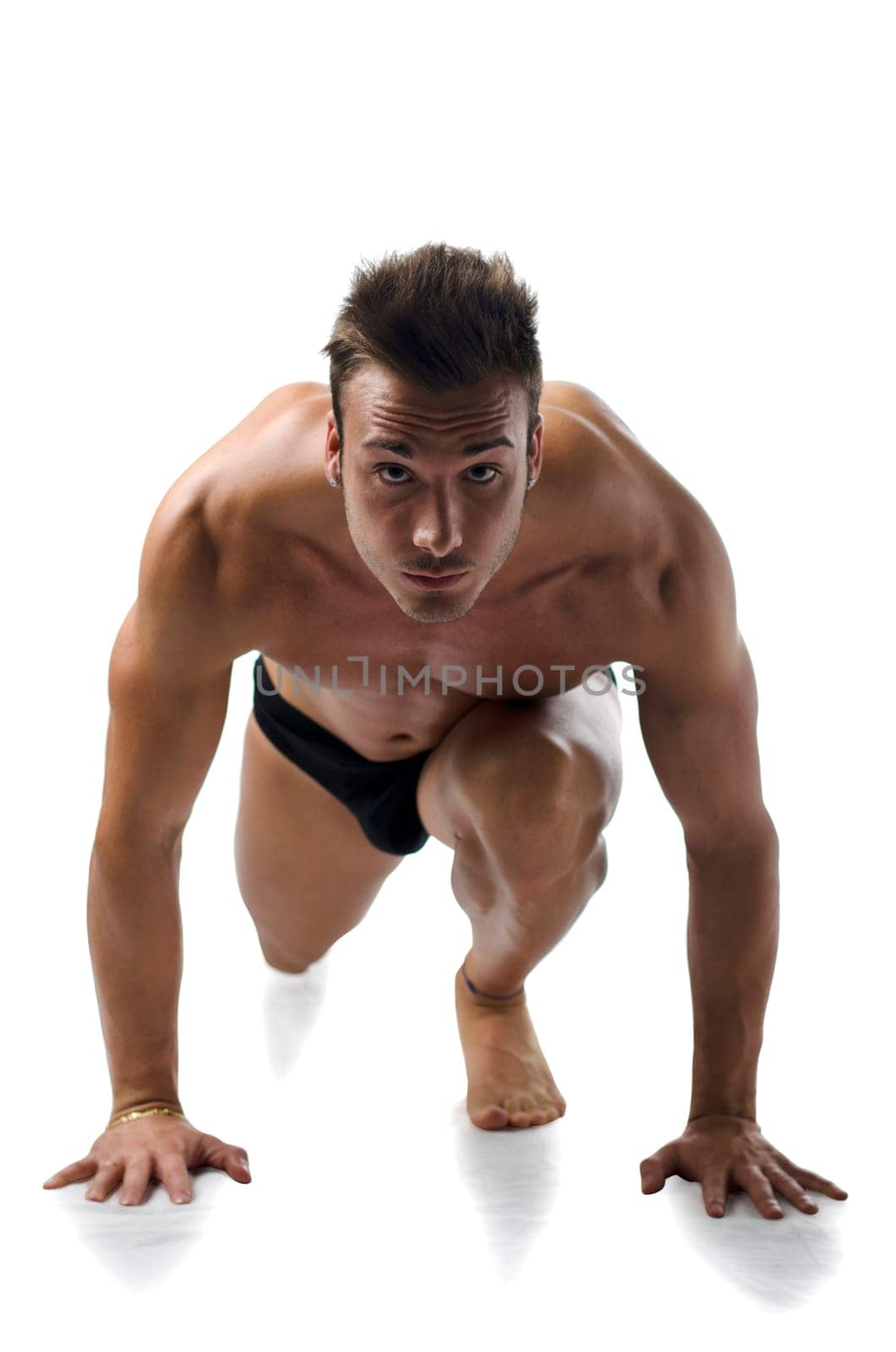 A muscular shirtless young man ready to sprint and run