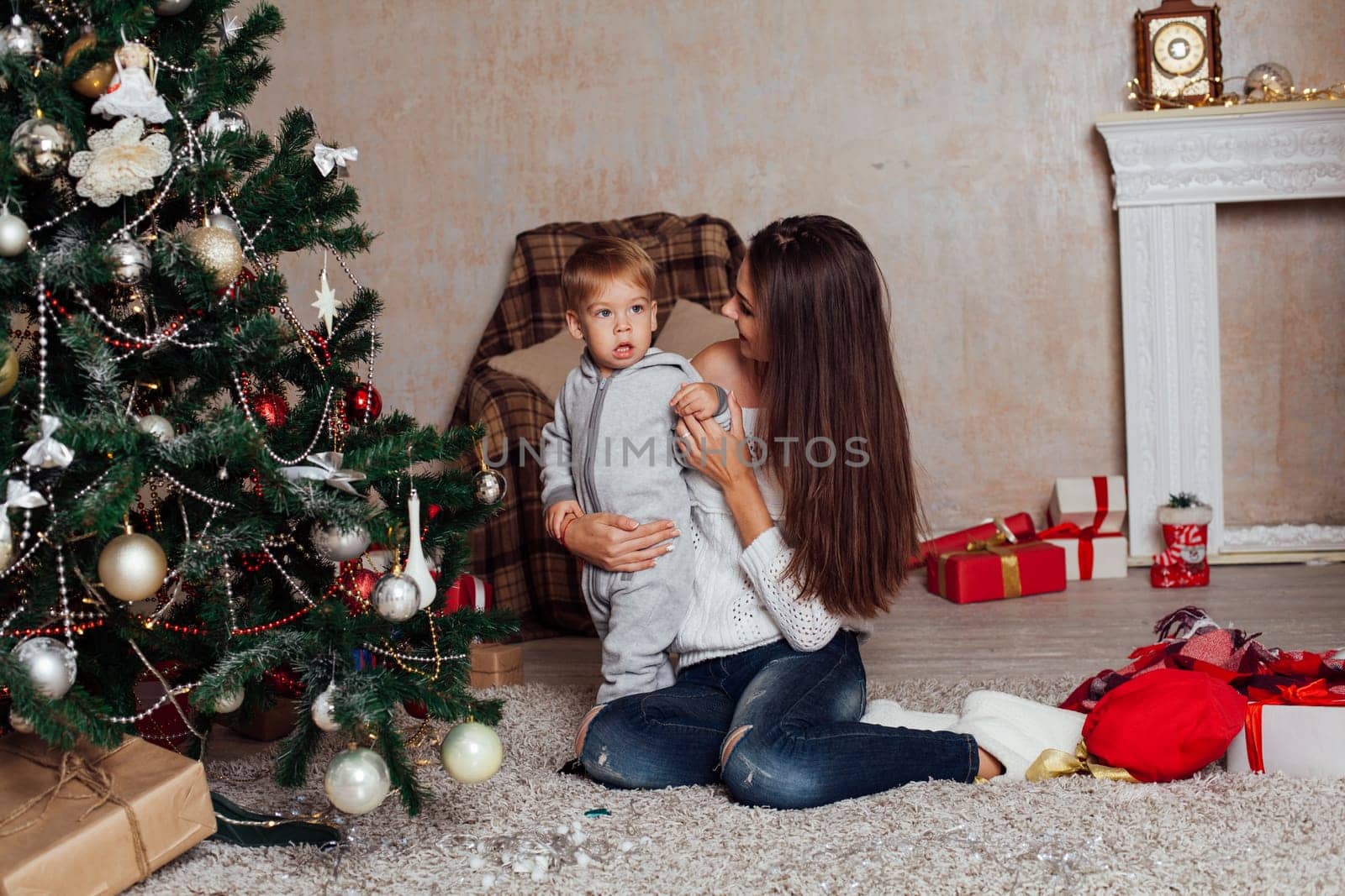 mother and little boy at Christmas tree with gifts 1 by Simakov