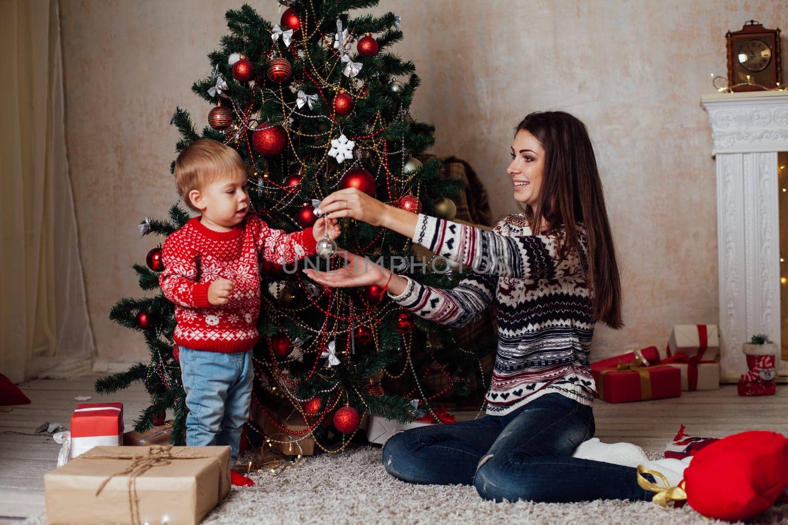 mom with son decorate tree on new year's Gifts Christmas by Simakov