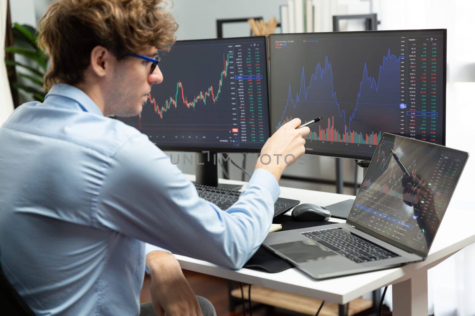 Young investor in stock trader pointing on dynamic exchange rate on laptop and pc screen in dynamic market graph online in real time at modern home office, analyzing financial technology data. Gusher.