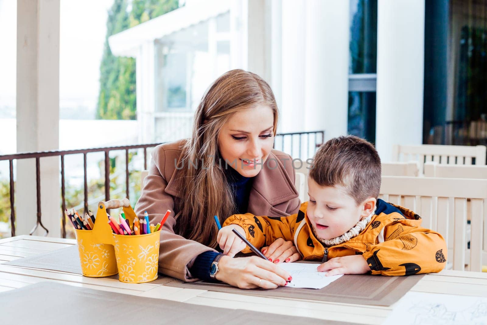 woman teaches the boy to draw with colored pencils 1