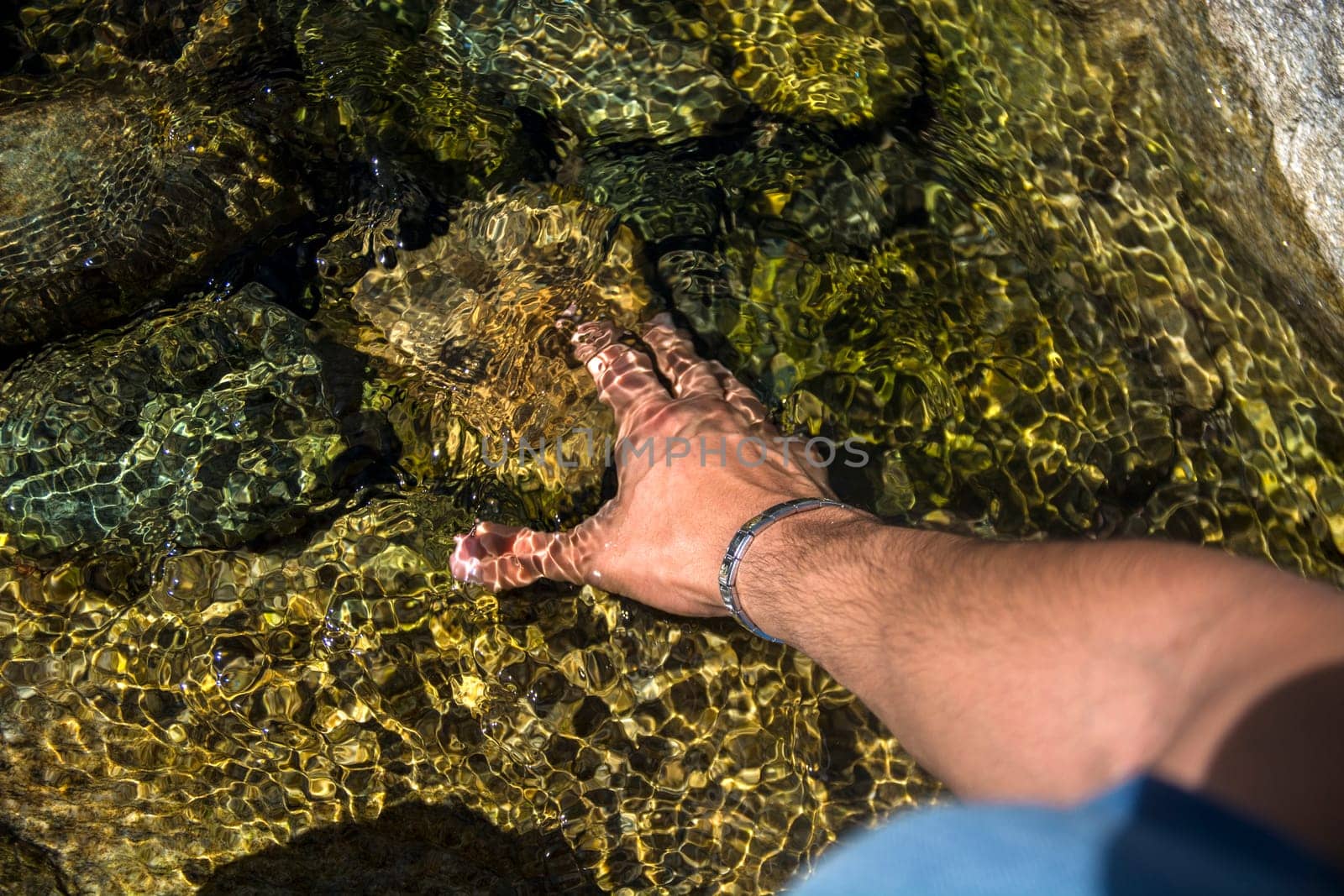 Photo of a man's hand reaching for something in the water by artofphoto
