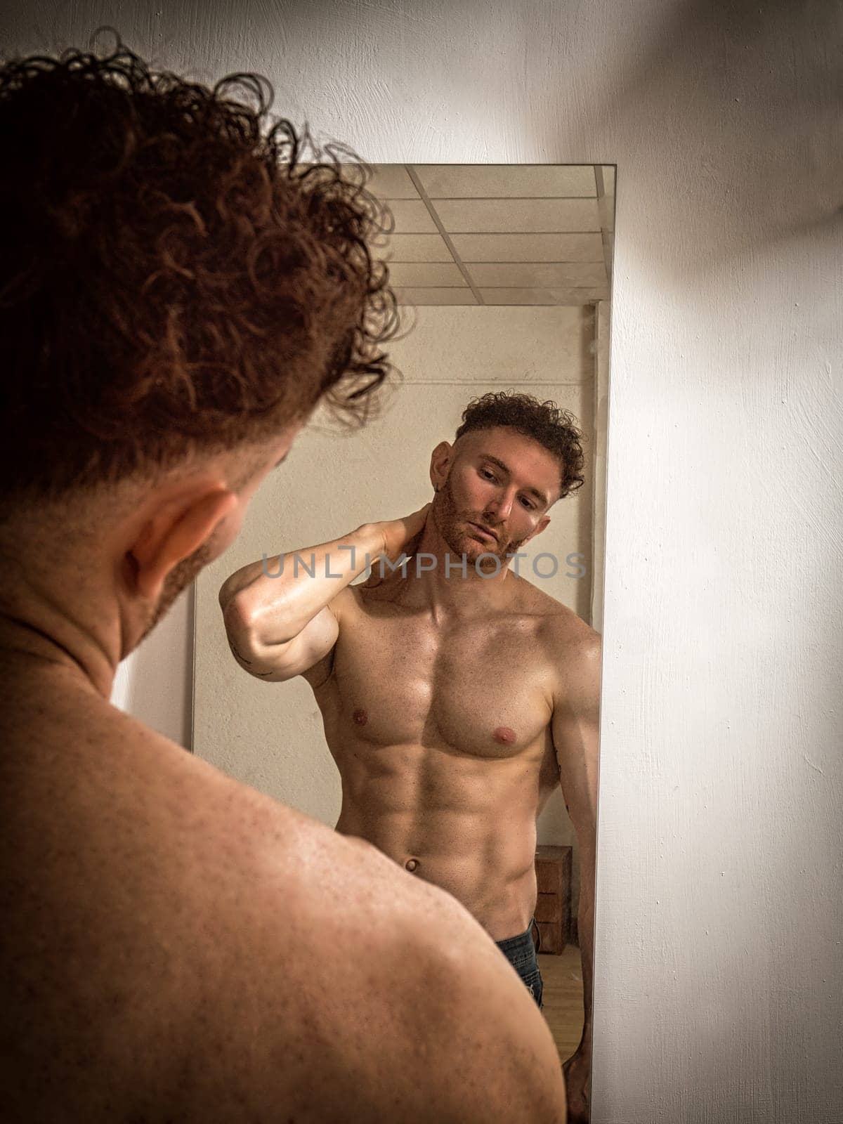 Photo of a muscular man admiring his reflection in the mirror by artofphoto