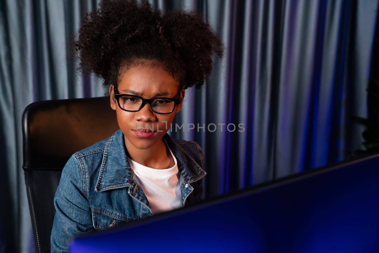 Young African American creator woman with serious face, thinking carefully and looking at final project document on laptop for planing next sequence. Concept of work at neat home place. Tastemaker.