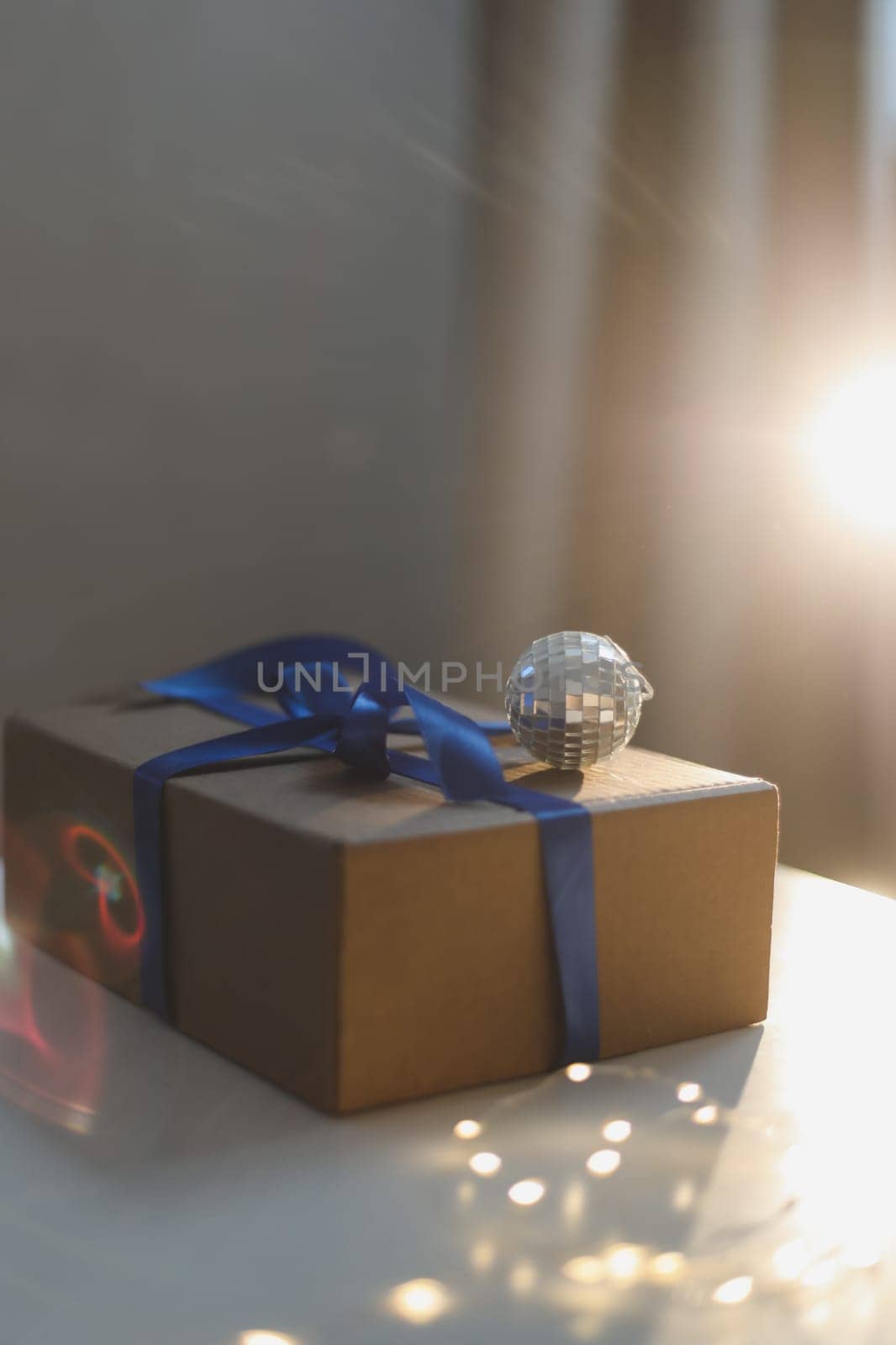 craft paper gift box with blue satin ribbon bow on table background by paralisart