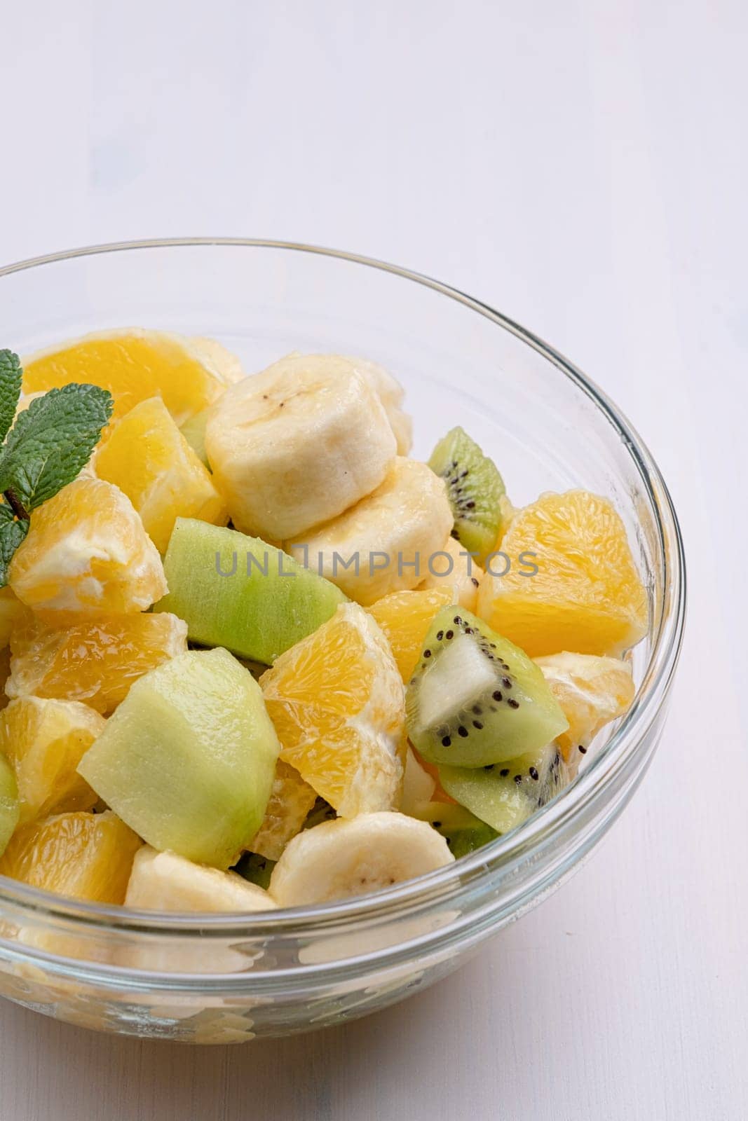 Bowl of healthy fresh fruit salad on white background by Desperada