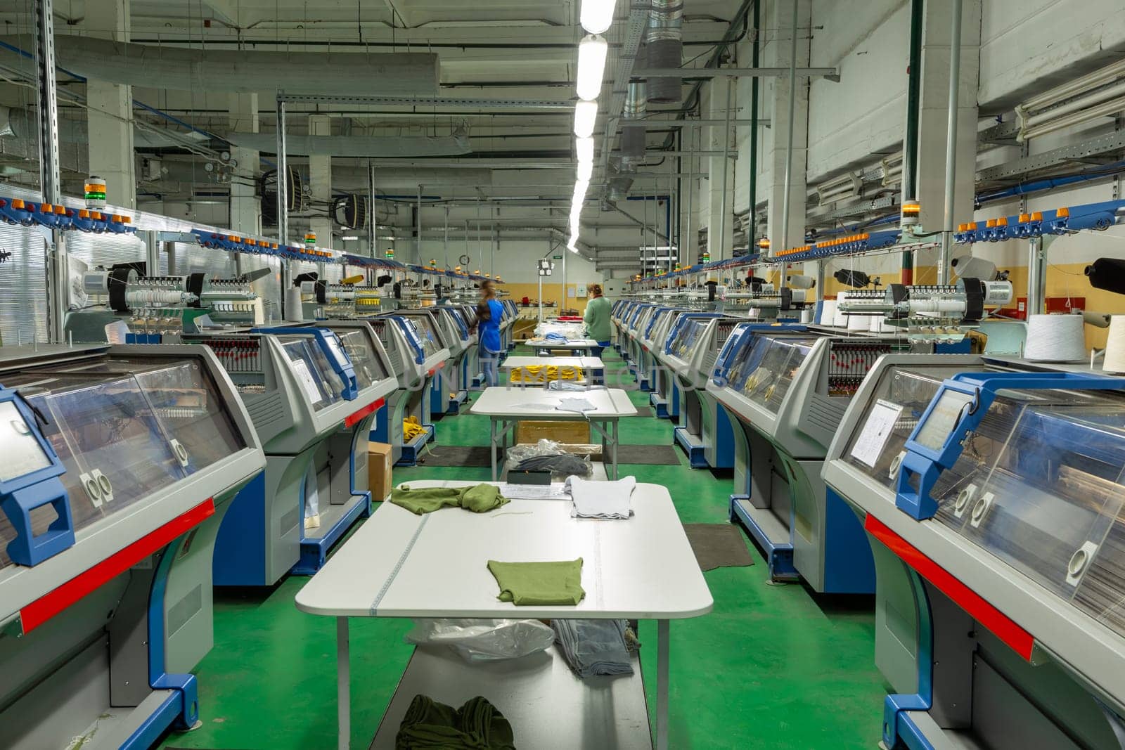 A row of industrial textil flat knitting machines in a knitwear factory. by BY-_-BY