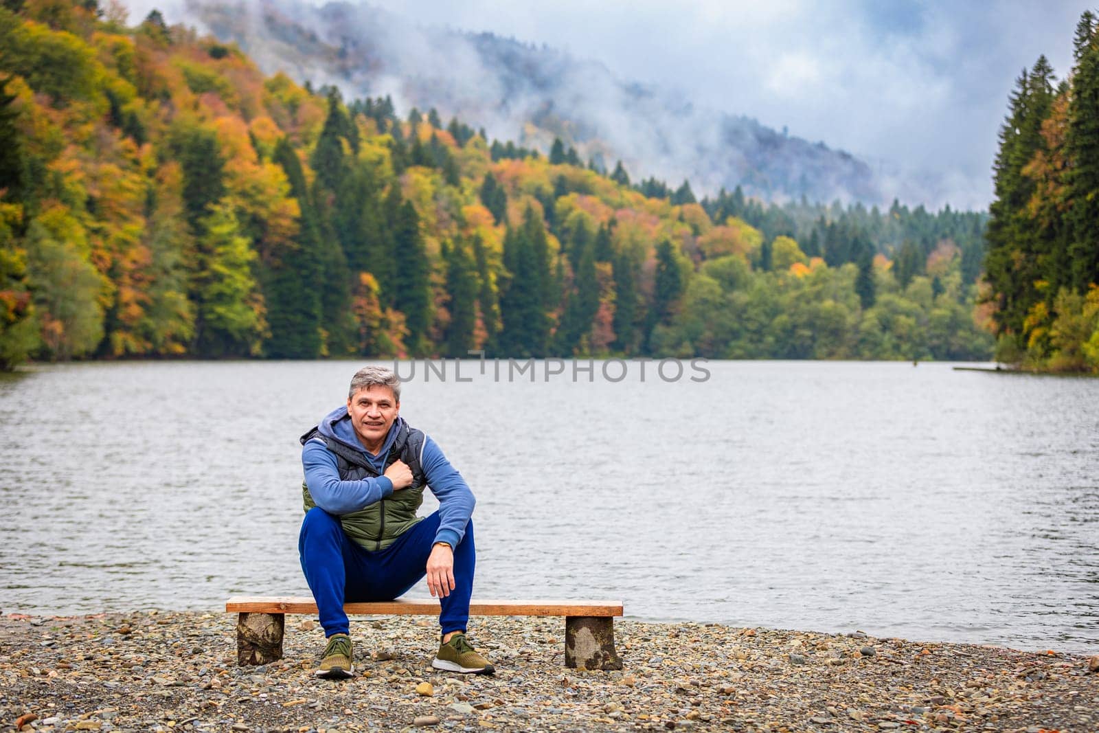 The man admires the picturesque landscapes by the lake in the mountains, surrounded by the beauty of nature and the comfort of the mountain landscape.