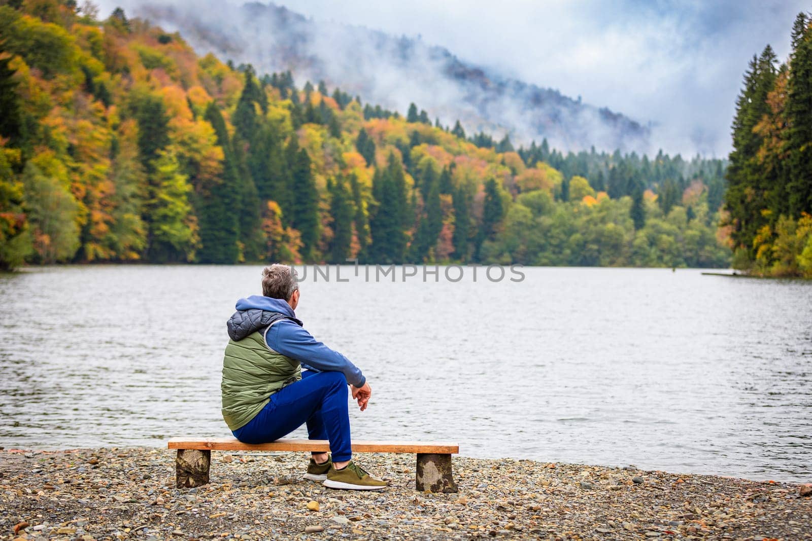 A man is delighted with a picturesque lake in the mountains, surrounded by beautiful natural landscapes.