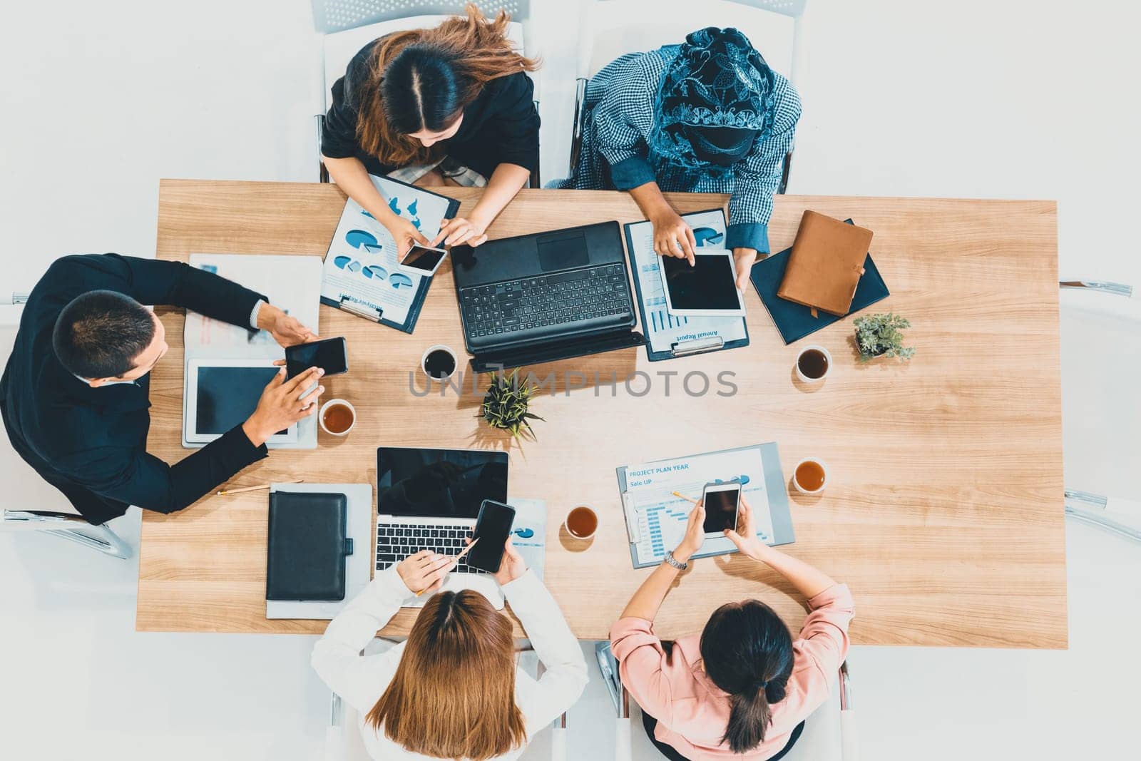 Top view of businessman executive in group meeting with other businessmen and businesswomen in modern office with laptop computer, coffee and document on table. People corporate business team uds