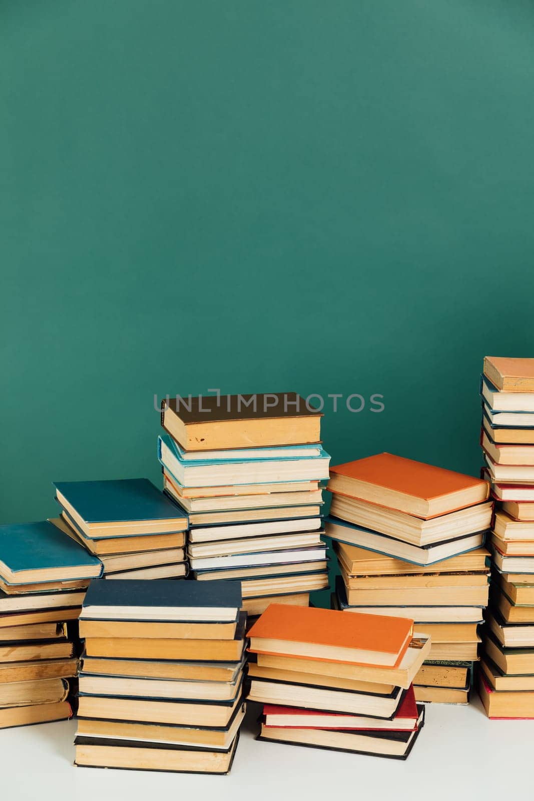 Stacks of educational books in university library on green background