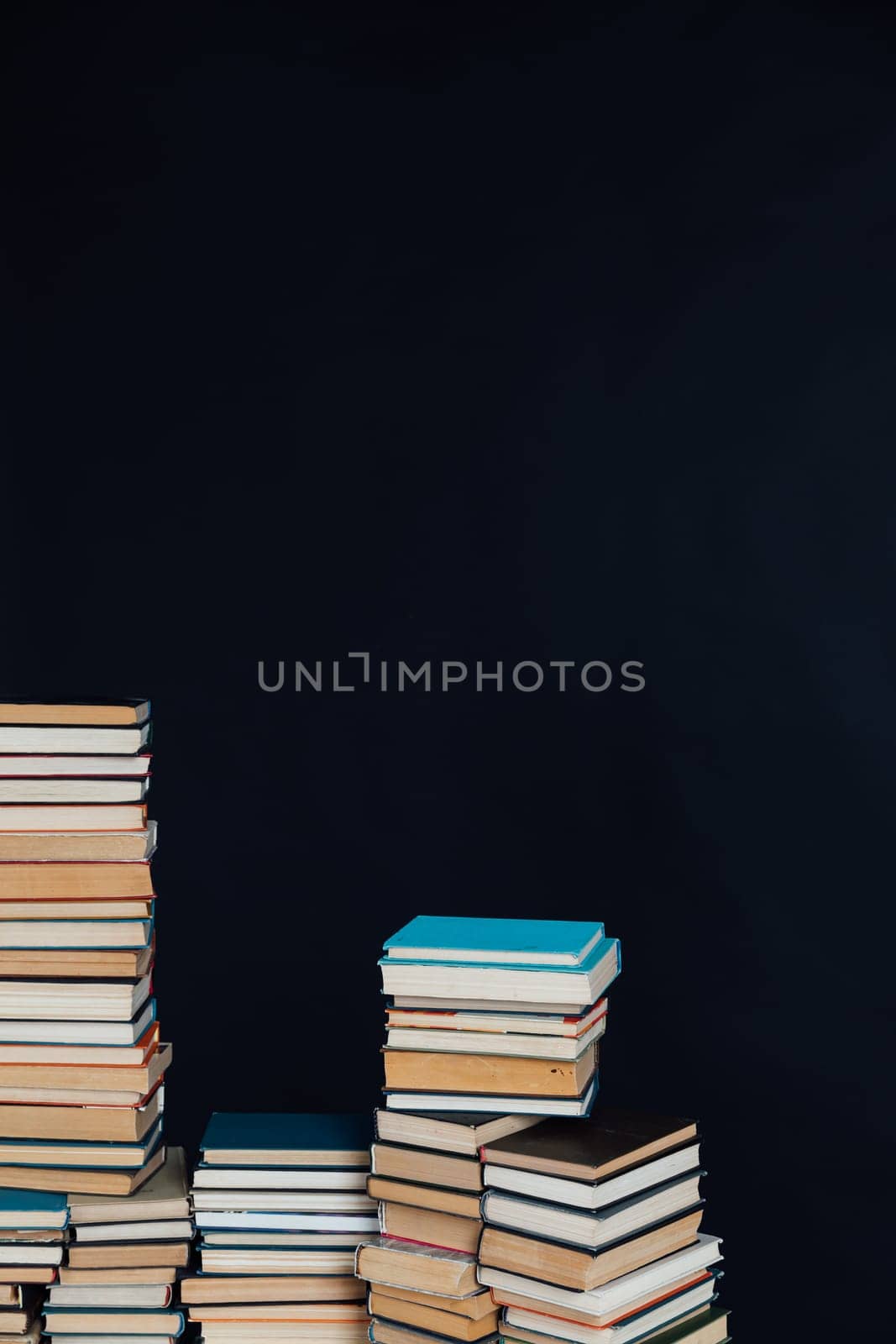 Stacks of educational books in school library on black background by Simakov