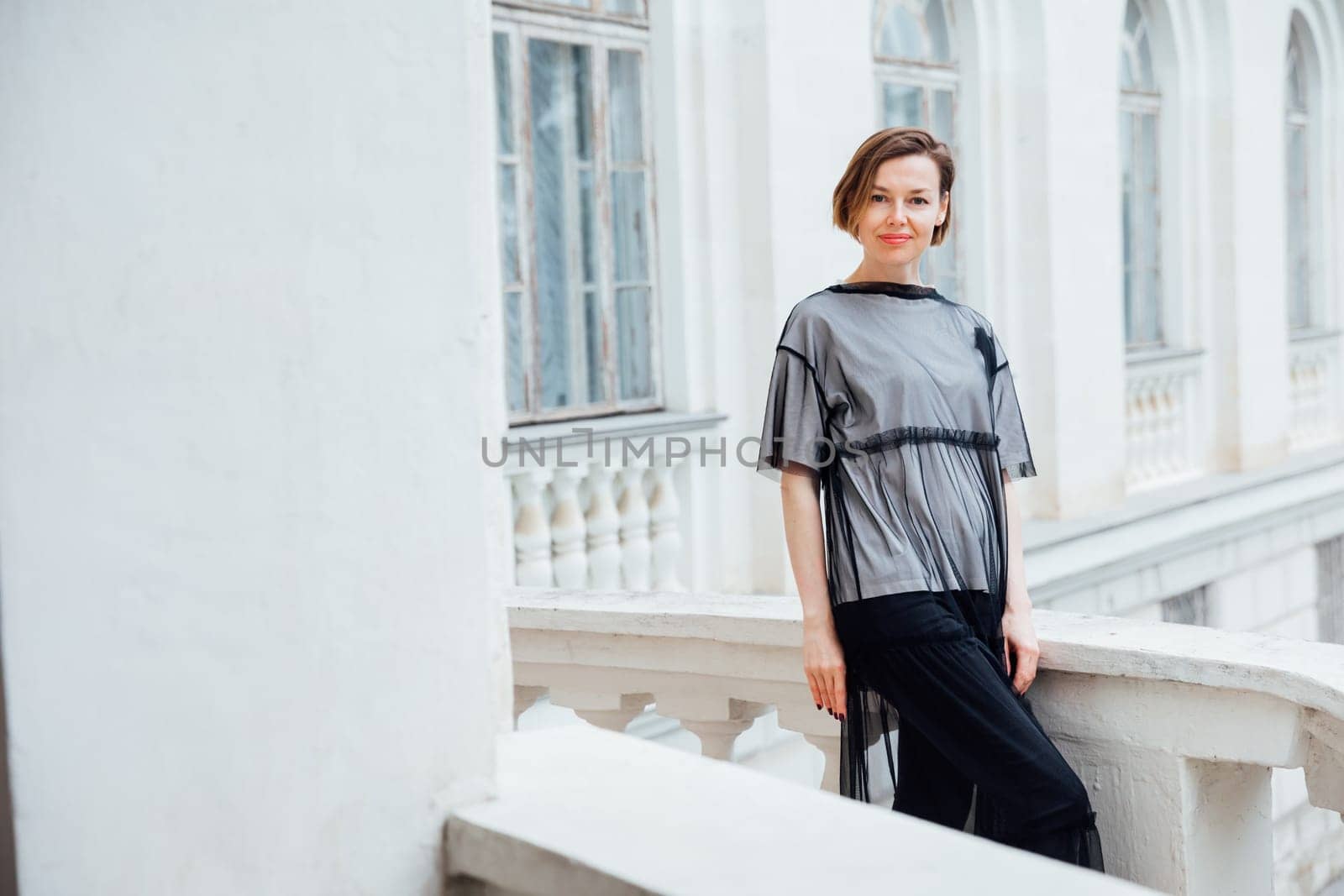 woman in black clothes posing near a white building