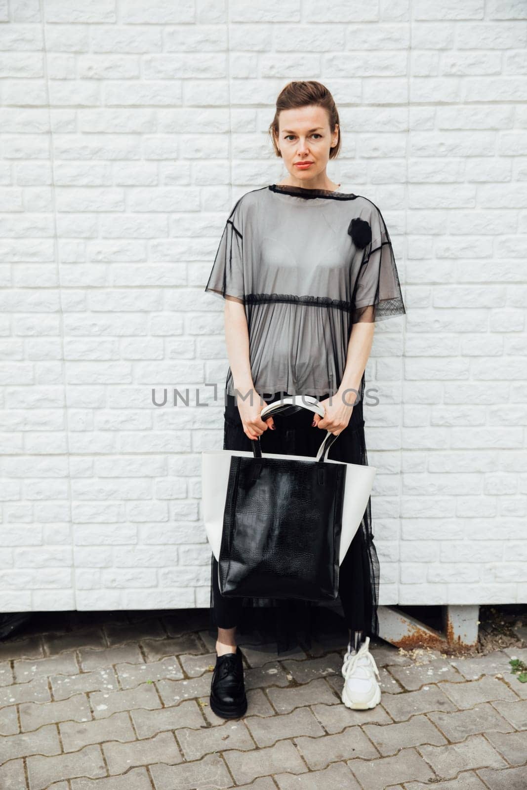 woman in black clothes posing near a white building