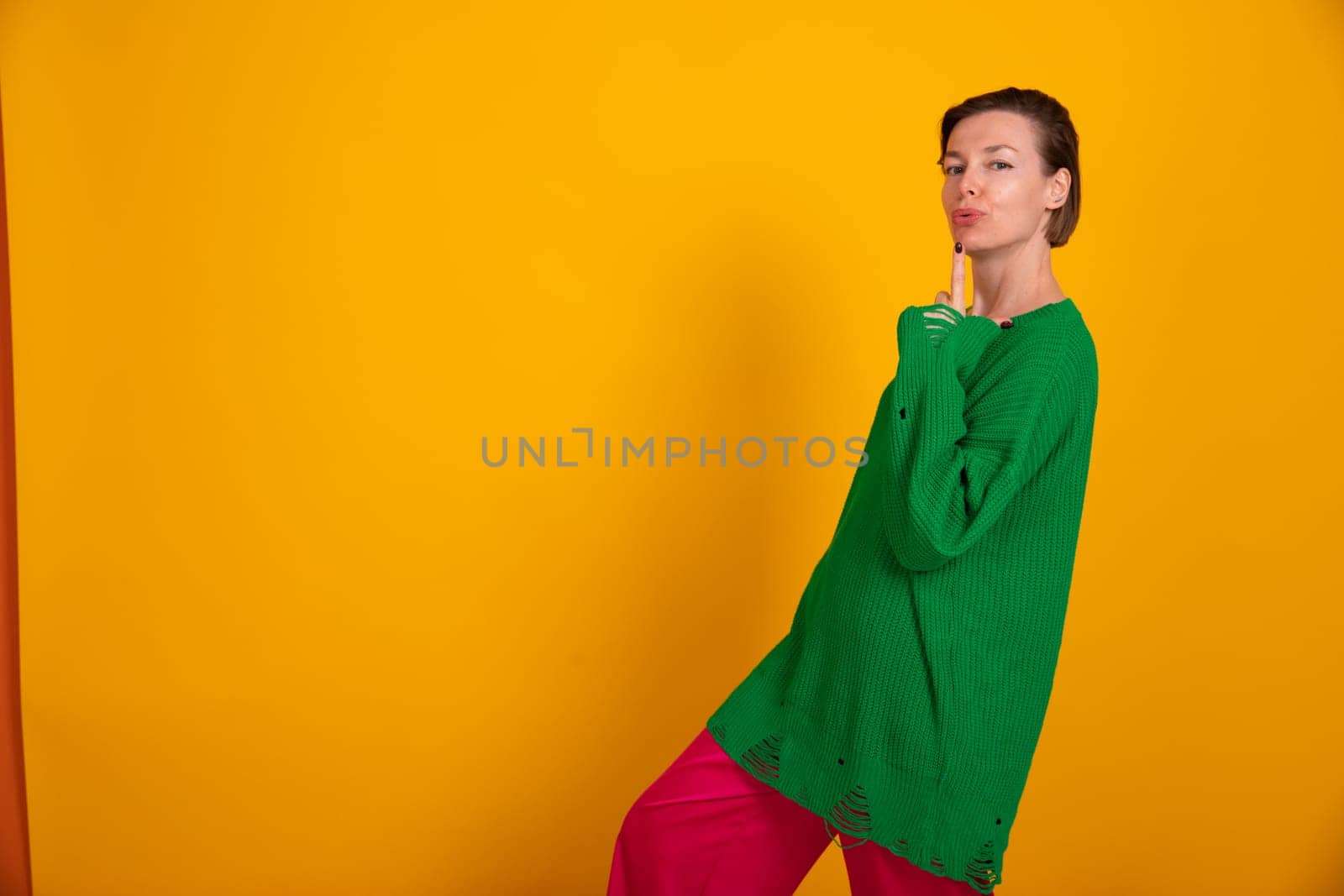 Beautiful fashionable woman in green sweater on yellow autumn background by Simakov
