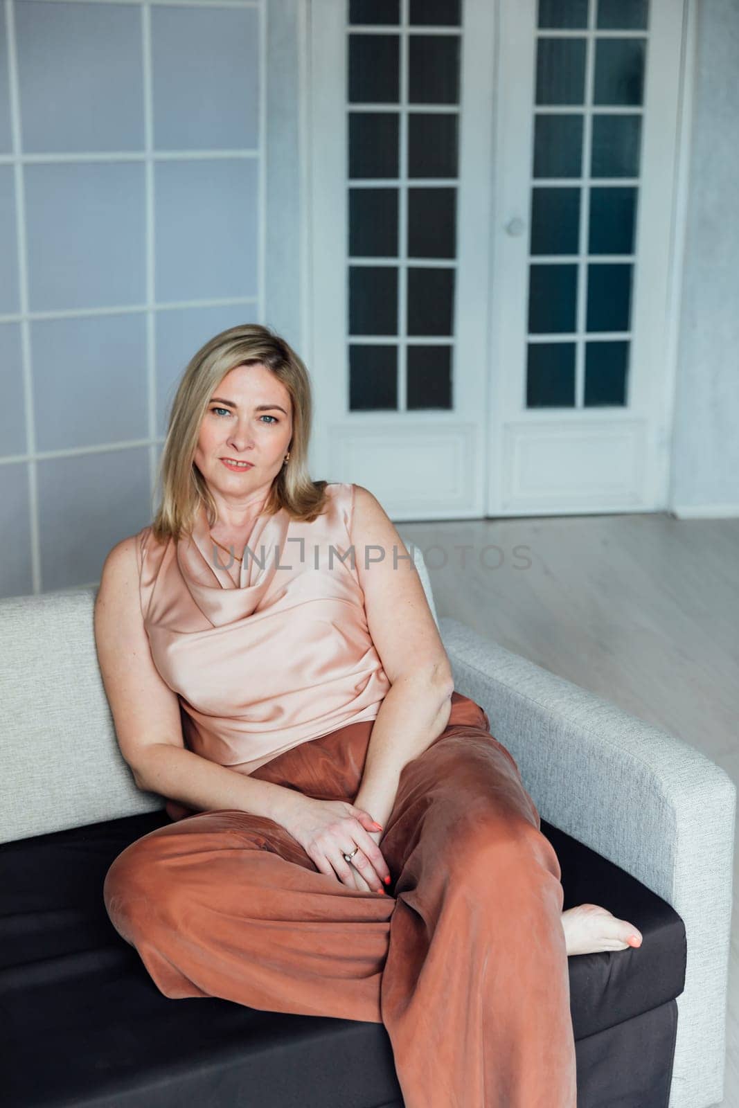 Adult woman sitting on sofa in office by Simakov