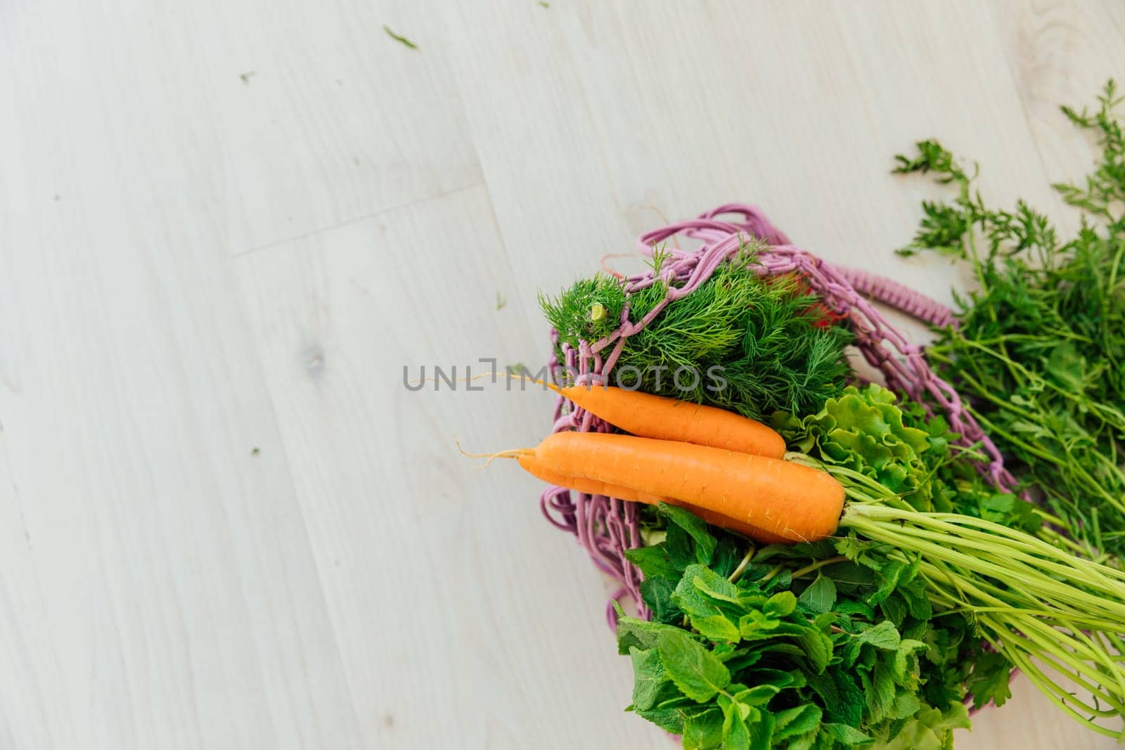 Fresh vegetables carrots and herbs in a bag on a gray table as background by Simakov