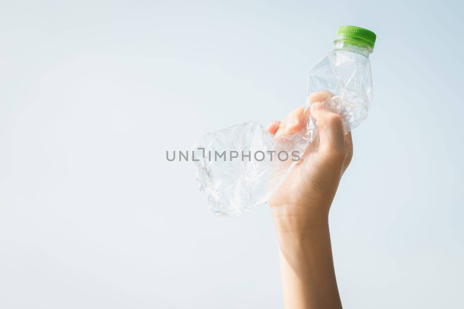 Recyclable plastic bottle held in hand up on sky background. Hand holding plastic waste for recycle reduce and reuse concept to promote clean environment with effective recycling management. Gyre