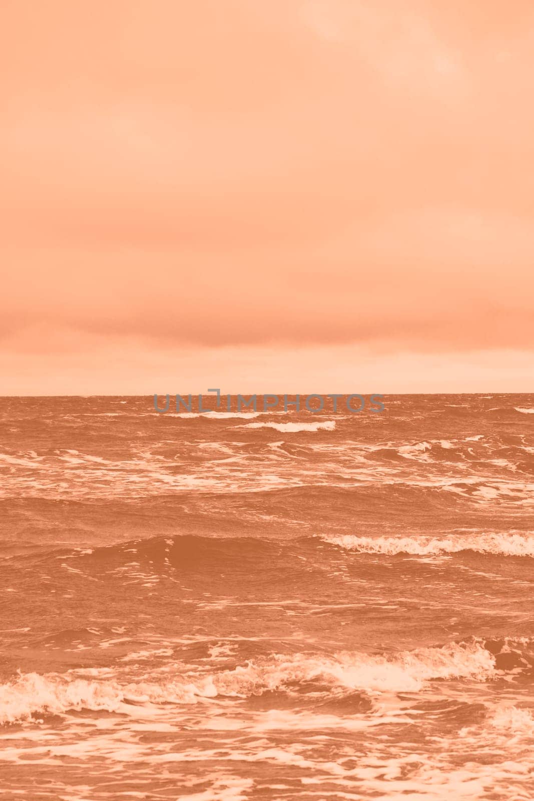 Peach fuzz toned sea beach. North sea. Stormy weather: strong waves, gloomy sky, sea foam. Trendy colour 2024. by kizuneko