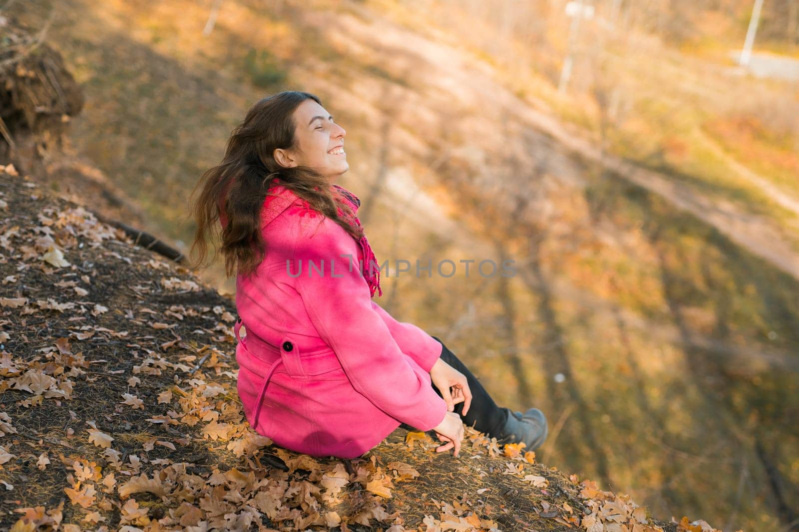 Beautiful happy smiling girl with long hair wearing pink jacket posing in autumn park. Outdoor portrait day light. Autumn mood concept. Generation Z and gen z youth. Copy empty space for text. by Satura86