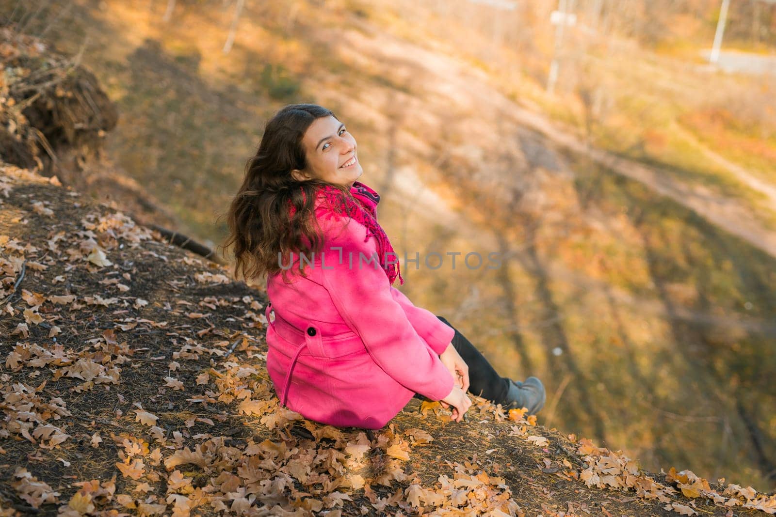 Beautiful happy smiling girl with long hair wearing black hat and pink jacket posing in autumn park. Outdoor portrait day light. Autumn mood concept. Copy empty space for text.