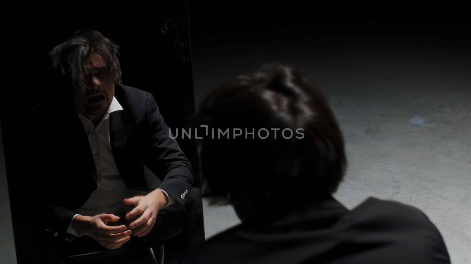 Desperate annoyed european man in rage and anger tearing his hair out. Stock footage. I made a terrible mistake, emotions in front of the mirror on a black background
