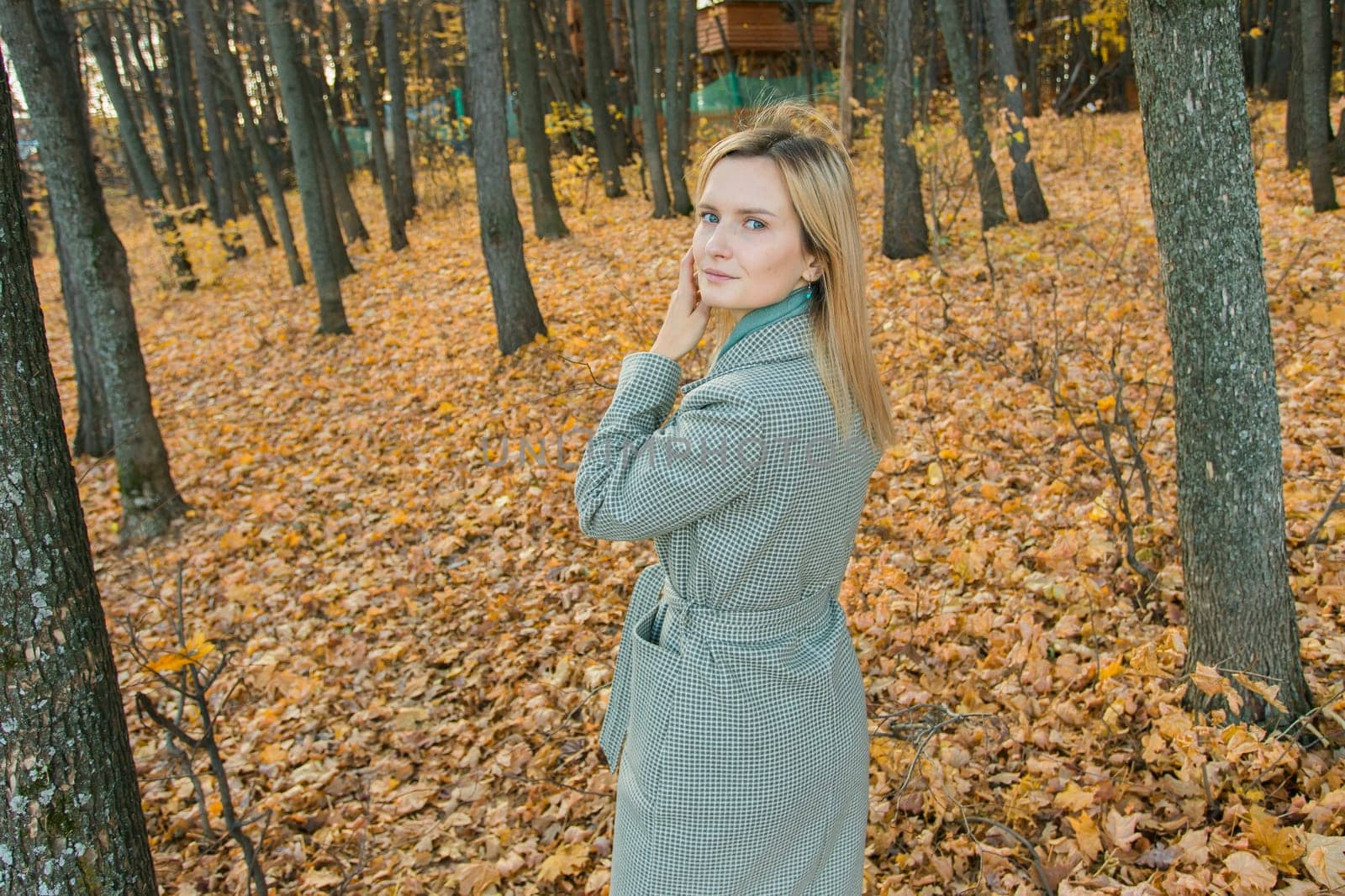 Blonde woman in elegant gray coat walks in the sunny autumn season park copy space mockup. Generation z and gen z youth concept. by Satura86