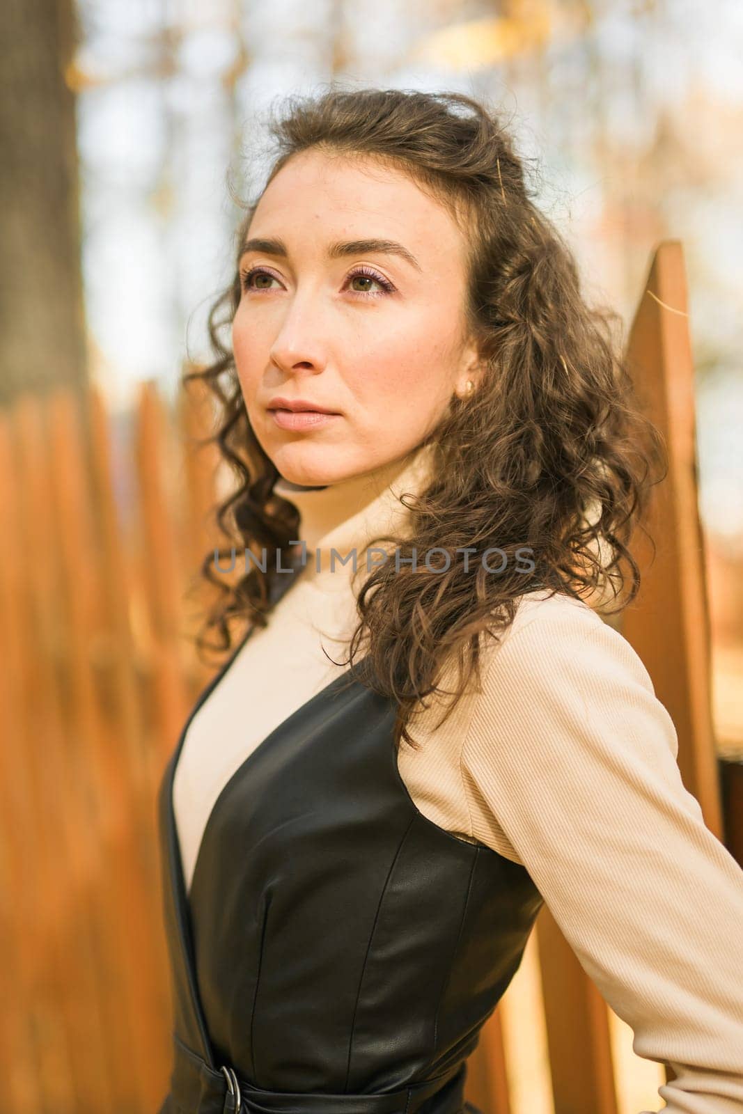 Autumn portrait of a beautiful happy curly woman in fall season. Millennial generation female. Natural beauty