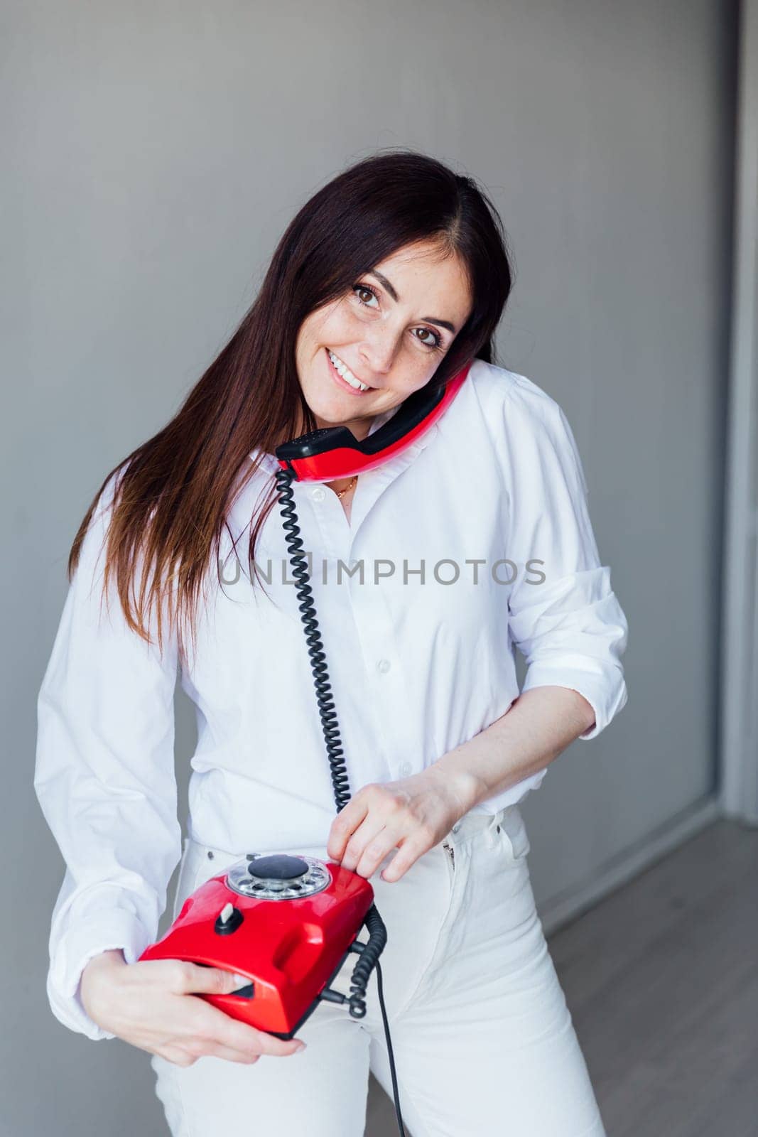 Brunette woman talking on old wired phone by Simakov