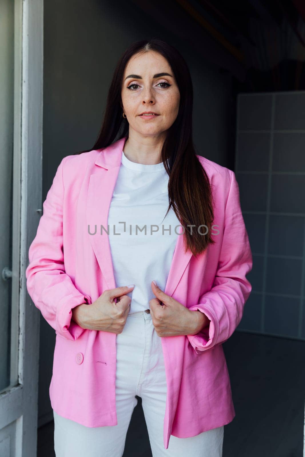 fashionable brunette woman in pink jacket and white pants