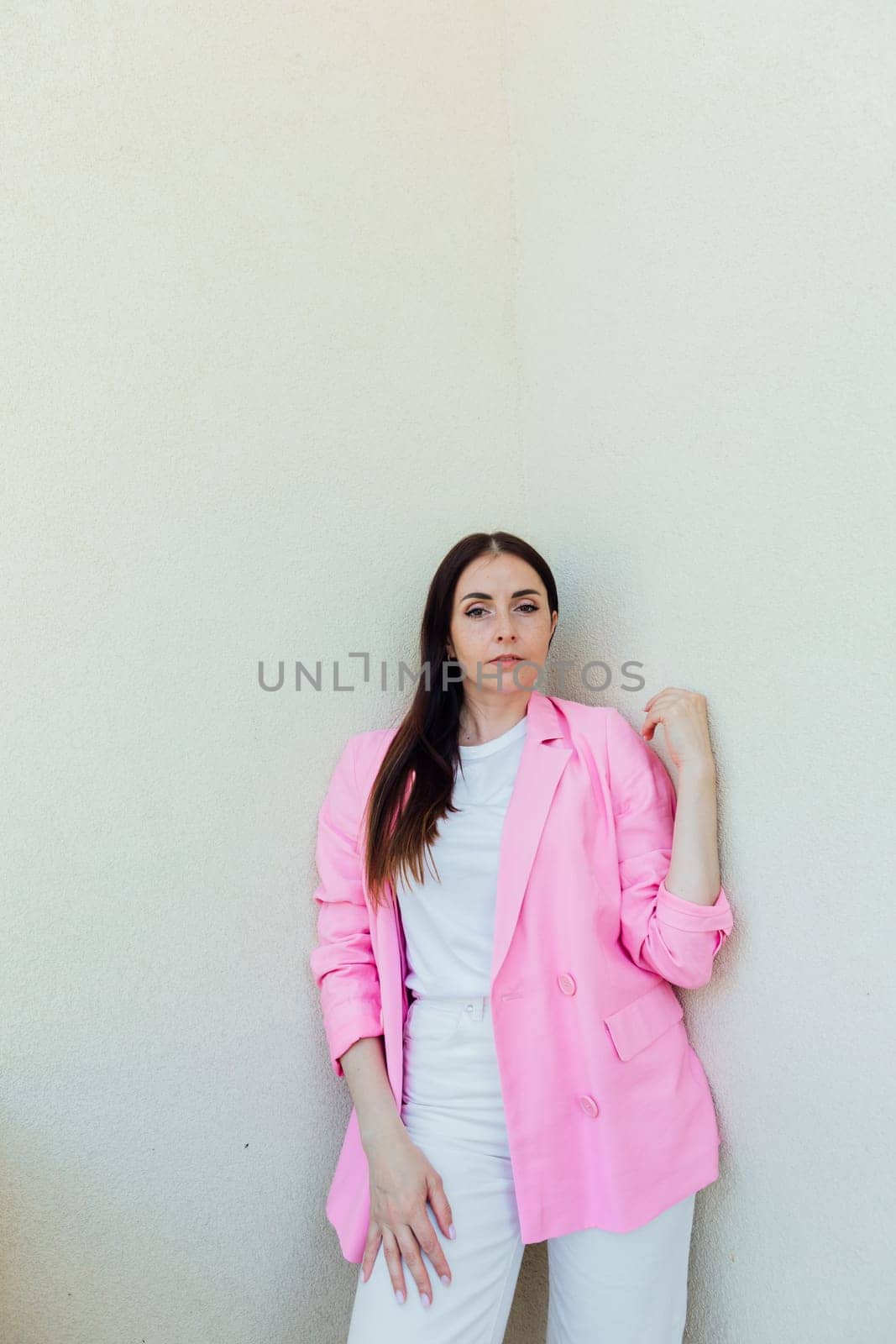 fashionable brunette woman in pink jacket and white pants