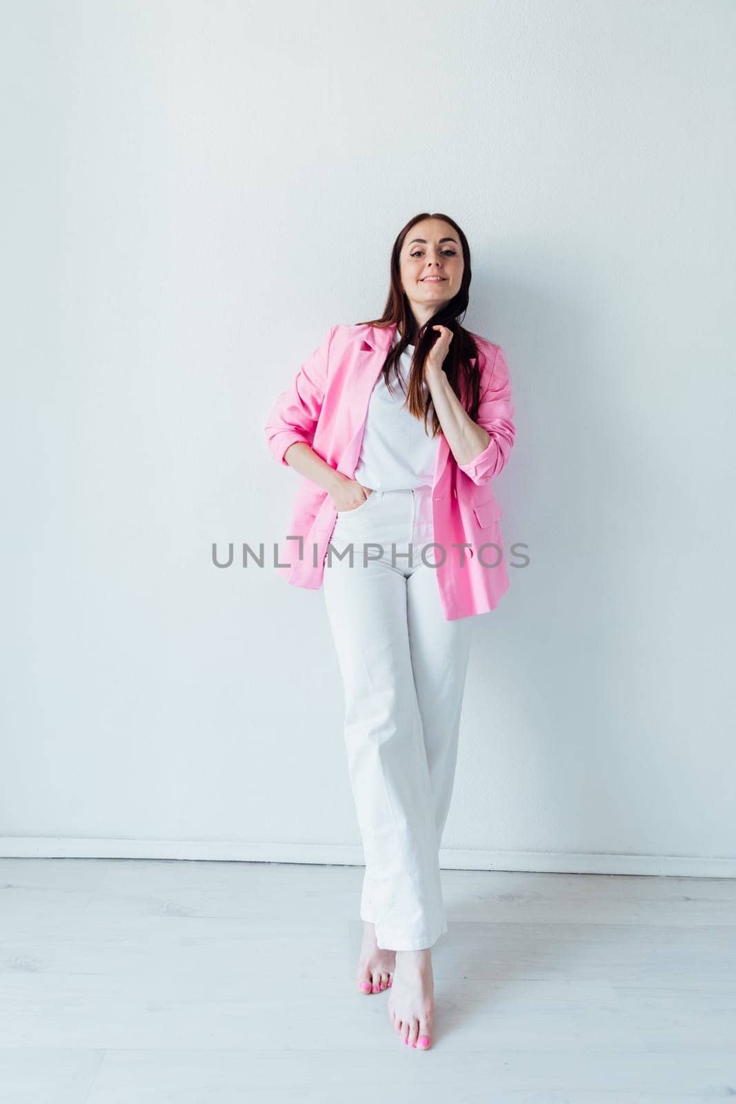 Beautiful fashionable brunette woman in pink jacket and white pants by Simakov