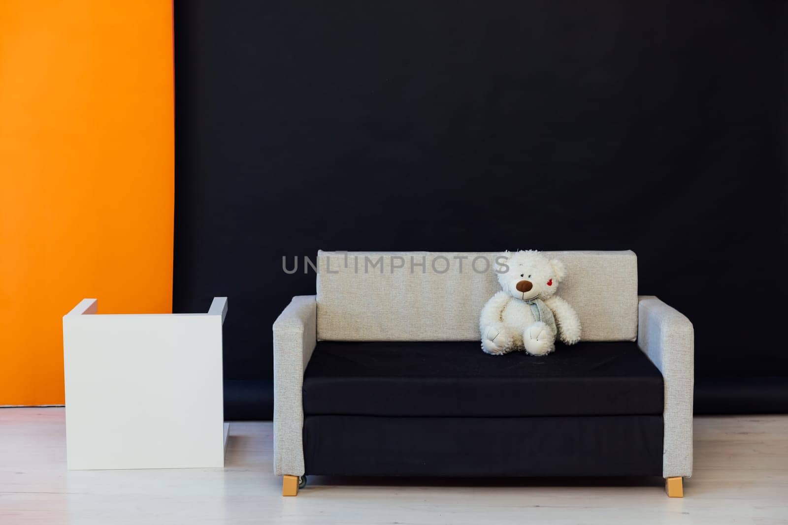 Grey sofa in the interior of a black and orange room by Simakov