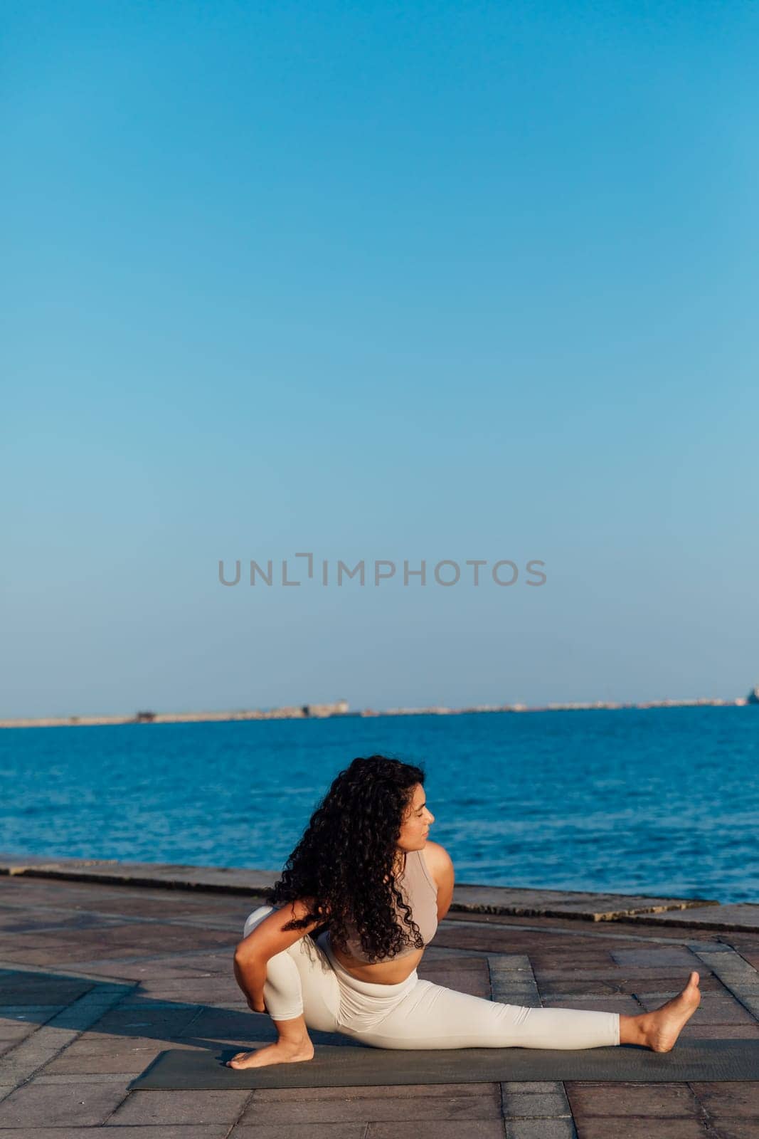 Woman doing yoga asana breathing practice on the beach by the sea by Simakov